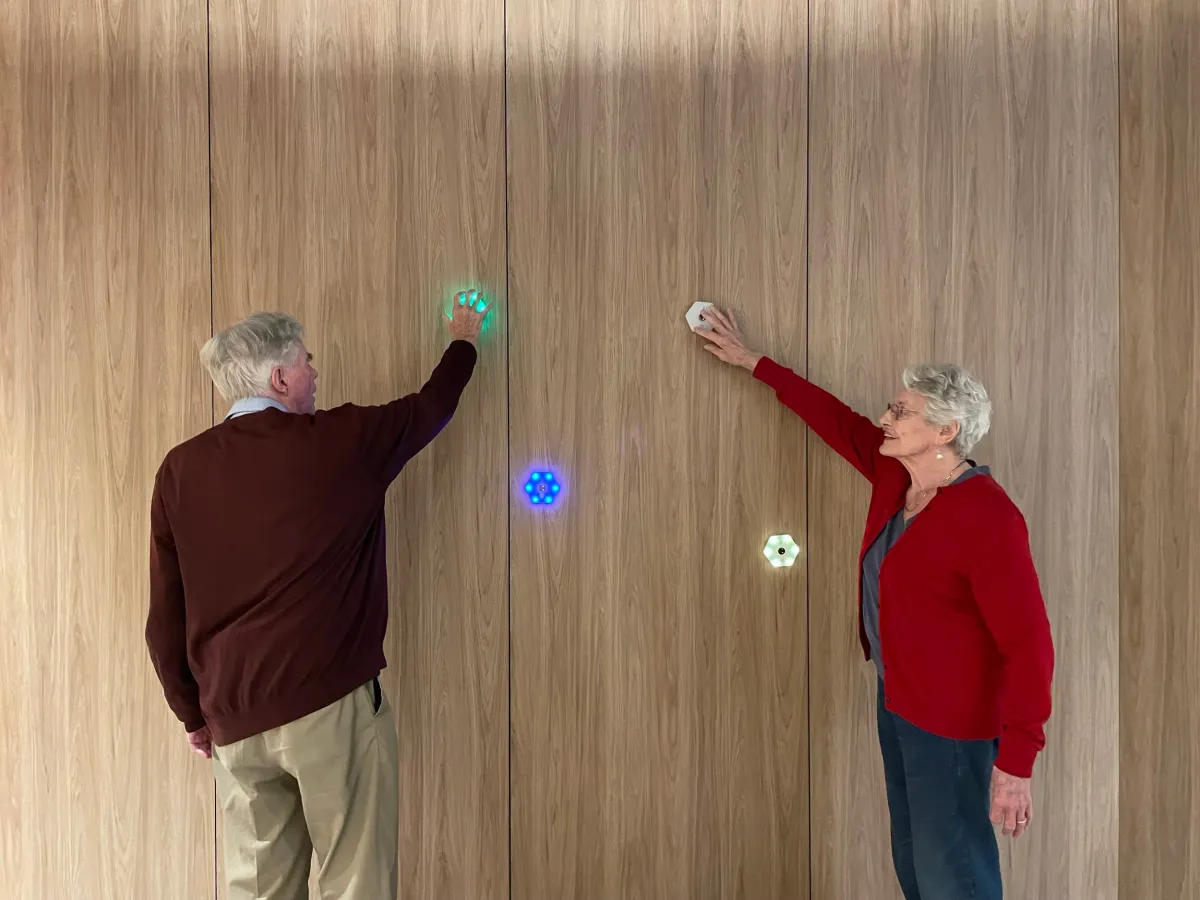 Older adult exercising with light equipment, physiotherapist assisting